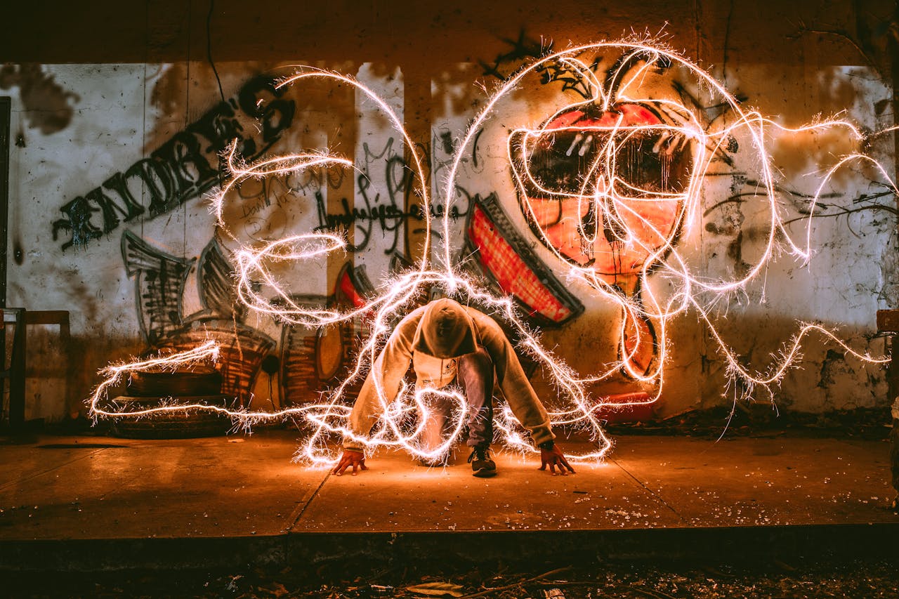 Home A person kneeling in front of graffiti creates light painting with energy and flair at night.