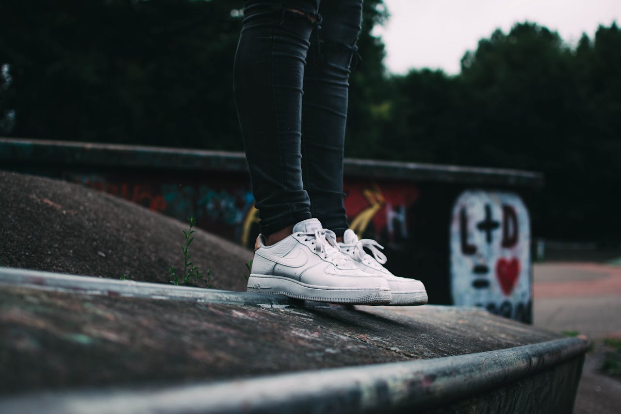Home Close-up of white sneakers on a graffiti backdrop in an outdoor urban setting.